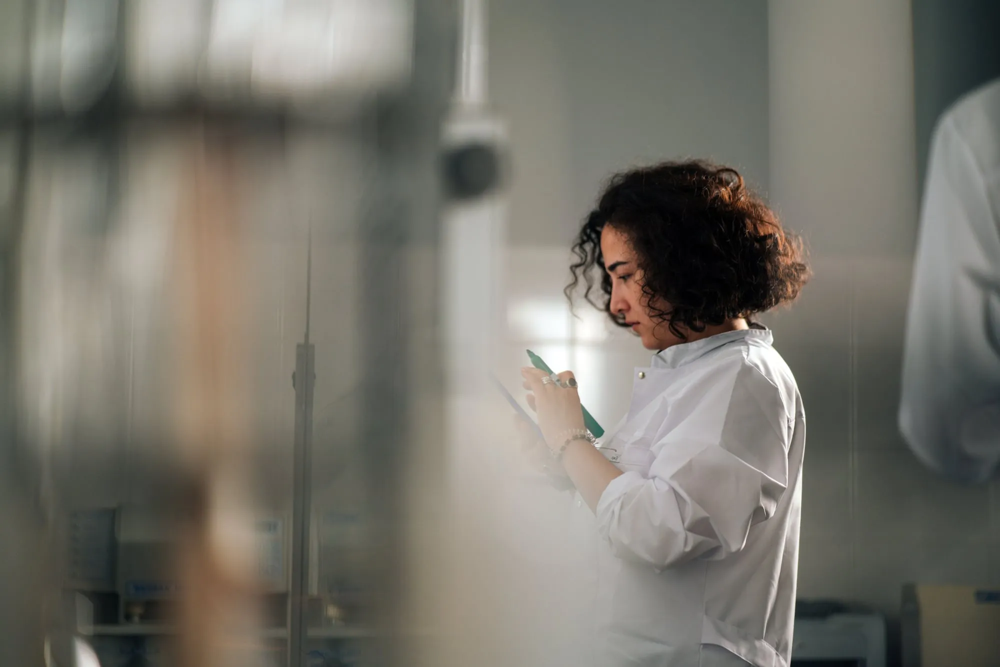A woman in a white shirt reading from a phone in a glass office