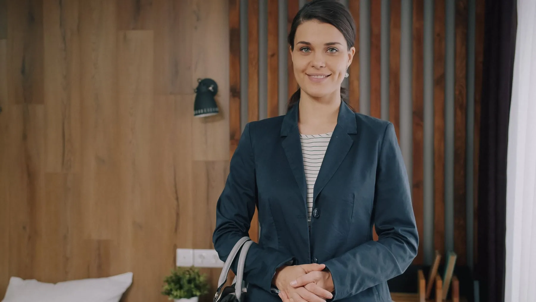 A smiling woman in a dark blazer standing in a wood-panelled office